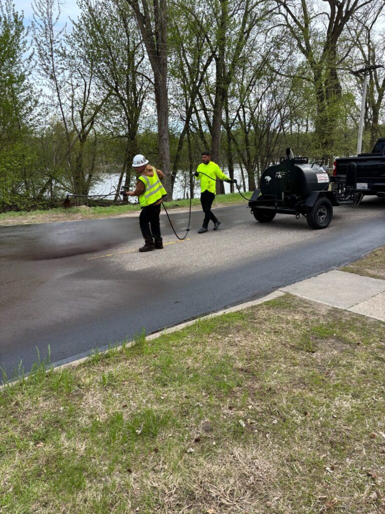 Perfect Path Pavers crew spraying sealcoat on asphalt
