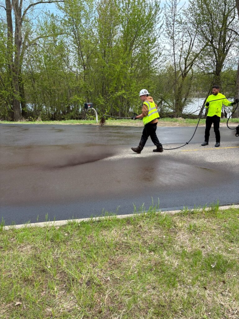 Perfect Path Pavers crew spraying sealcoat on asphalt